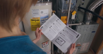 A woman looks at a checklist with a water heater in the background.